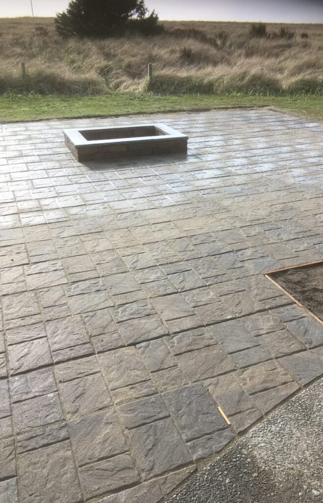 Custom masonry fire pit centered in a large hardscape patio in Seaside Oregon